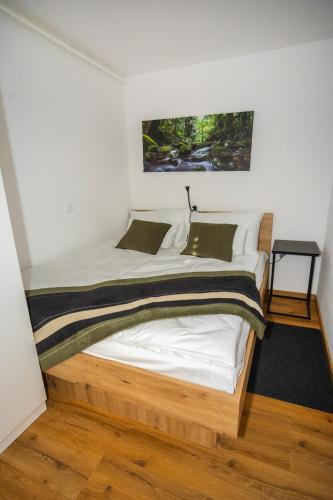 a bedroom with a wooden bed with a painting on the wall at Skalca Serenity Apartments Bled in Bled