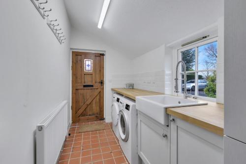 a kitchen with a sink and a washing machine at The Orchard - North East Escapes in Morpeth