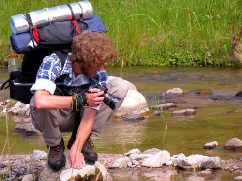 a man with a backpack taking a picture of a river at Estancia Altos del Durazno in Estancia Grande