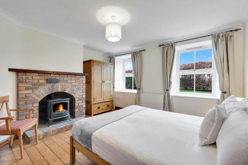 Un dormitorio con una cama y una chimenea. en The Orchard - North East Escapes, en Morpeth