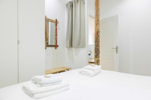 La salle de bains est pourvue de serviettes blanches sur un lit et d'un miroir. dans l'établissement Loft Moderne et Spacieux - 6 Couchages Voltaire 11, à Paris