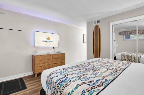 Un dormitorio con una cama y un televisor en una pared. en Summer Sands - 108 by Sea Scape Properties, en Wrightsville Beach