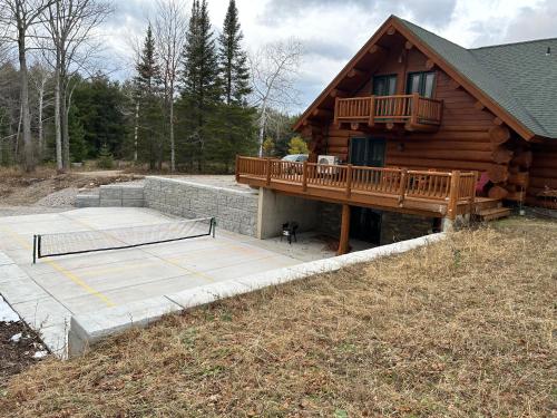 a house with a wooden deck and a tennis court at Log Retreat at Fish Creek by Simple Life Rentals in Fish Creek