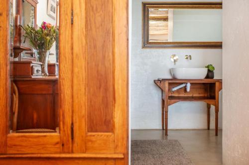 a bathroom with a wooden door and a sink at Die Pomphuisie in Paternoster