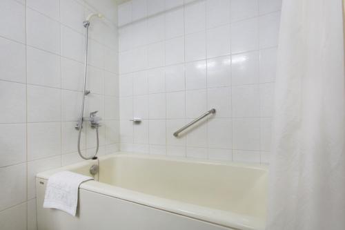 La salle de bains blanche est pourvue d'une baignoire et d'une douche. dans l'établissement Libero Hotel, à Busan