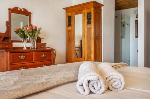 a bedroom with towels on a bed with a mirror at Die Pomphuisie in Paternoster