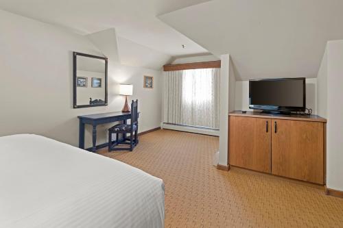 a bedroom with a bed and a tv and a desk at von Trapp Family Lodge & Resort in Stowe