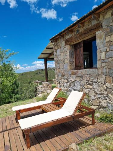 two lounge chairs on a deck in front of a stone building at Estancia Altos del Durazno in Estancia Grande