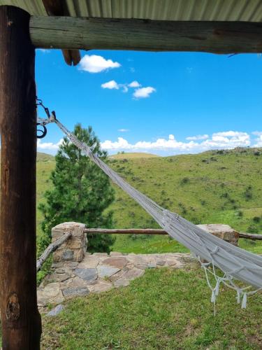 a hammock hanging from a wooden pole in a field at Estancia Altos del Durazno in Estancia Grande