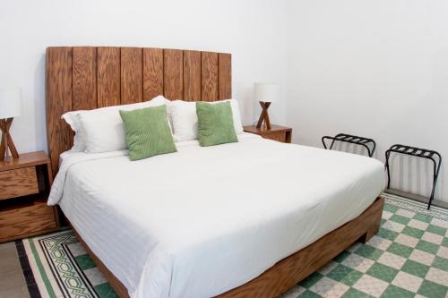 a bedroom with a large white bed with green pillows at Casa Monarcas - Victoria (with AC) in Guadalajara