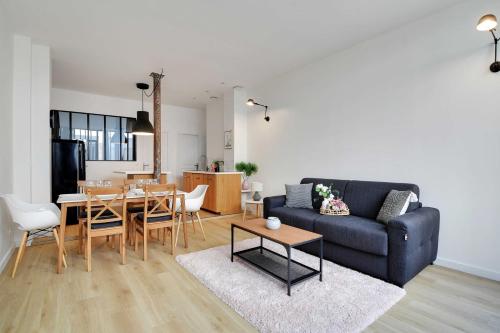 un salon avec un canapé et une table avec des chaises dans l'établissement Loft Lumineux et Design - 6 Personnes Voltaire 11e, à Paris
