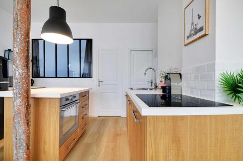 une cuisine avec un évier et un plan de travail dans l'établissement Loft Lumineux et Design - 6 Personnes Voltaire 11e, à Paris