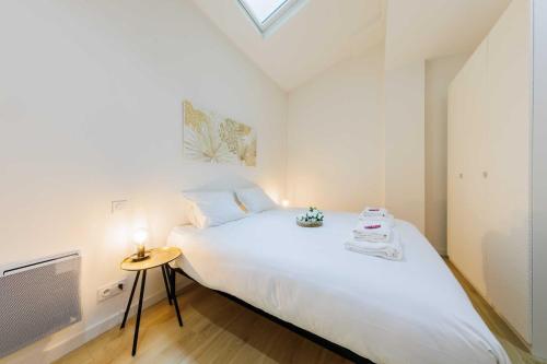 une chambre avec un grand lit blanc et une télévision dans l'établissement Loft Lumineux et Design - 6 Personnes Voltaire 11e, à Paris