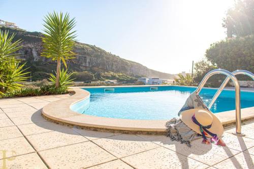 a swimming pool with a woman laying on a swing at Bleu Soleil By Ericeira Property in Mafra