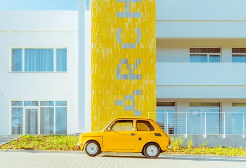 a small yellow car parked in front of a building at Arche Nałęczów & SPA dawne Sanatorium Milicyjne in Nałęczów