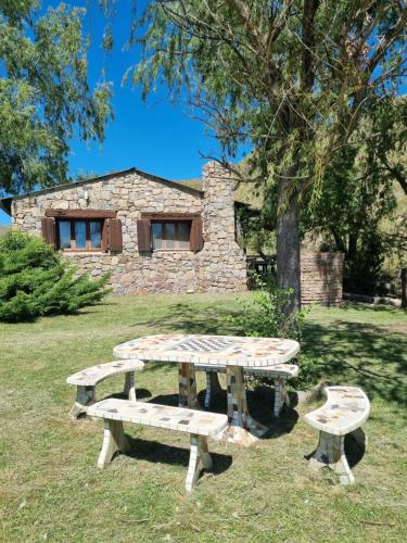 a picnic table and bench in front of a stone building at Estancia Altos del Durazno in Estancia Grande