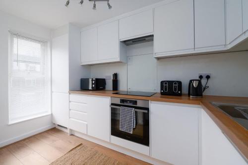 a white kitchen with white cabinets and a sink at GuestReady - Relaxing retreat near Tower Bridge in London