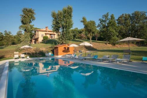 einen Pool mit Stühlen und Sonnenschirmen neben einem Haus in der Unterkunft Apartmanet Il Nido in Fucecchio