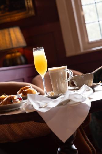 a table with a glass of orange juice and a plate of food at The Royal Forest - A Heartwood Inn in Chingford