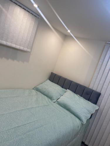 a bedroom with a bed with green sheets and a window at Newly Built Private Ensuite Room in Manchester