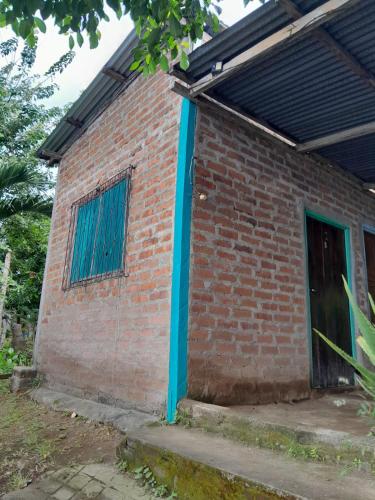 a red brick building with a blue door at Hostel Los Chocoyos in Ometepe
