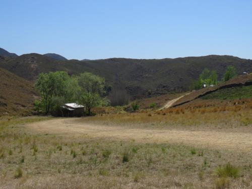 a barn in a field with mountains in the background at Estancia Altos del Durazno in Estancia Grande