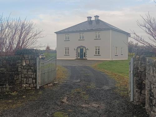 a white house with a gate and a driveway at Room 2 , Williamstown, Ireland in Crumlin