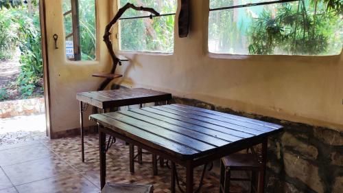 a wooden table and bench in a room with windows at Bela Oyá Casa Hostel in Vale do Capao