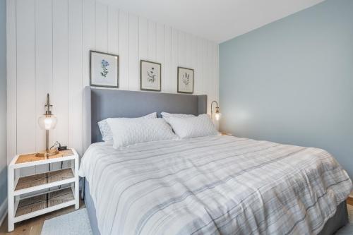 a white bedroom with a bed with a striped blanket at Vita Huset by Simple Life Rentals in Sister Bay