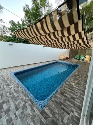 a swimming pool with a large umbrella over it at Casa Cristina Mamá Regañona in Bahías de Huatulco