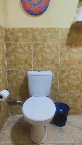 a bathroom with a white toilet and a blue trash can at Bela Oyá Casa Hostel in Vale do Capao
