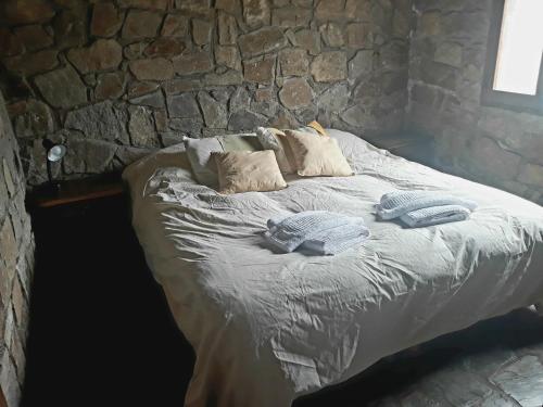 a bed in a stone room with pillows on it at Estancia Altos del Durazno in Estancia Grande