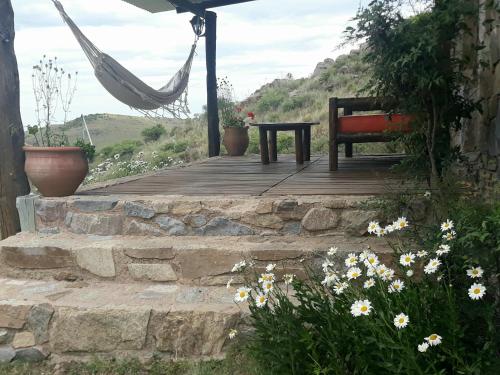 a bench and a hammock on a porch with flowers at Estancia Altos del Durazno in Estancia Grande