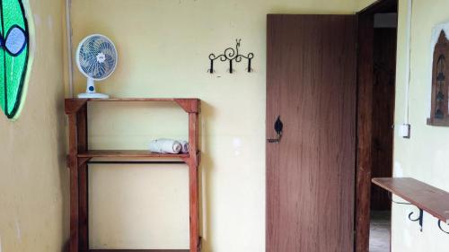 a room with a wooden shelf and a fan on the wall at Bela Oyá Casa Hostel in Vale do Capao