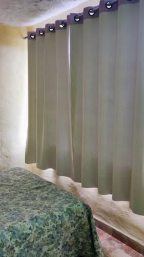 a bedroom with a bed and a window with curtains at Bela Oyá Casa Hostel in Vale do Capao