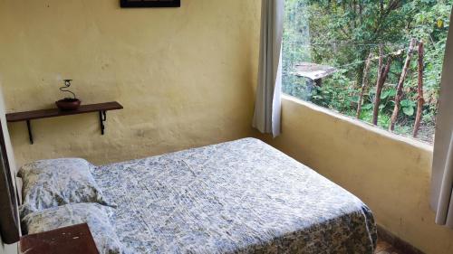 a small bedroom with a bed and a window at Bela Oyá Casa Hostel in Vale do Capao