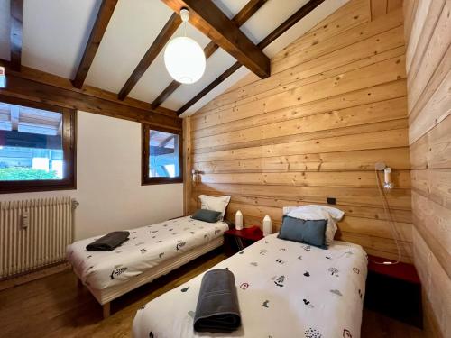 deux lits dans une chambre aux murs en bois dans l'établissement Arbois, à Megève