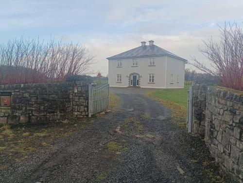 a white house with a stone fence and a road at Room 3 Williamstown, Ireland in Crumlin
