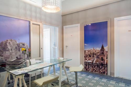 a dining room with a glass table and two windows at Matera In Vacanza in Matera