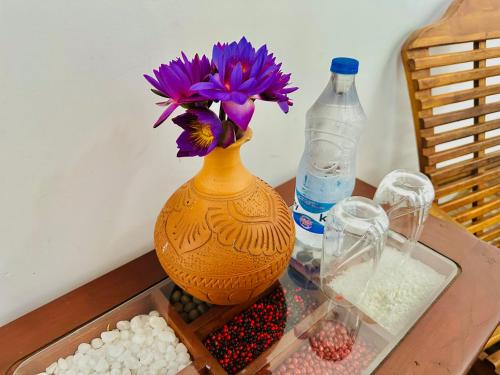 a vase with purple flowers in it on a table at Sunkis lagoon Bentota in Bentota