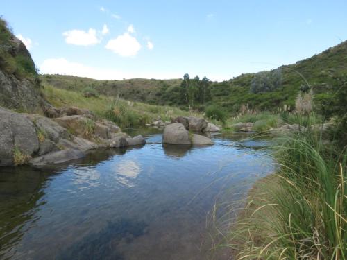 a river with rocks in the middle of a field at Estancia Altos del Durazno in Estancia Grande