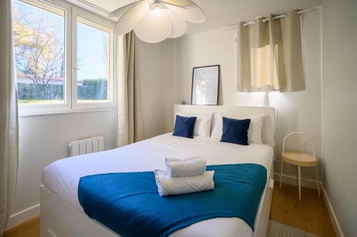 Un dormitorio con una gran cama blanca con almohadas azules. en OIQIA • Clarisse • Ivoire, en Castres