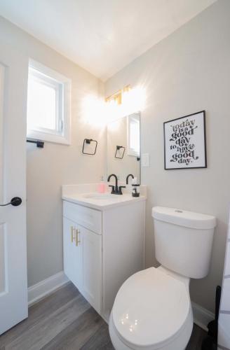 a white bathroom with a toilet and a sink at OV Mosaic - Golden Suite in North Camellia Acres
