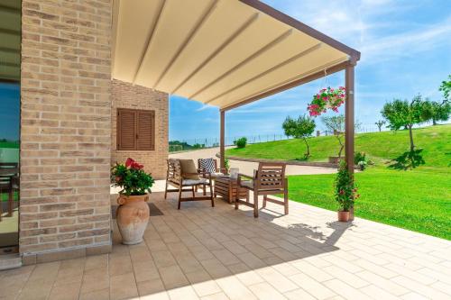 a patio with awning and chairs and a table at Italian Experience-Villa Clair in Fermo