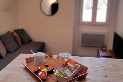 - un plateau avec des tasses et des collations sur une table en bois dans l'établissement Grand Studio Cosy au Cœur de Montpellier, à Montpellier