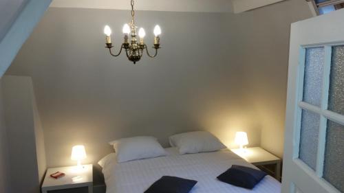 a bedroom with a white bed and a chandelier at B&B Charles Cabour in De Panne