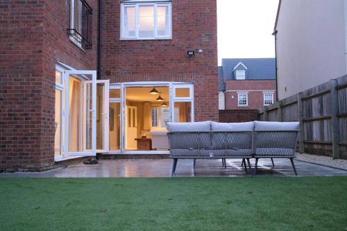 a bench on a patio in front of a brick building at Luxury 6-Bedroom House 5 minutes from Bicester Village Shopping Outlet - Perfect for Business and Family Stays! Private Parking for 4 Cars! in Chesterton