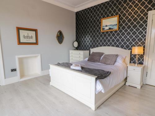 a bedroom with a white bed and a wall at Ailsa View in Girvan