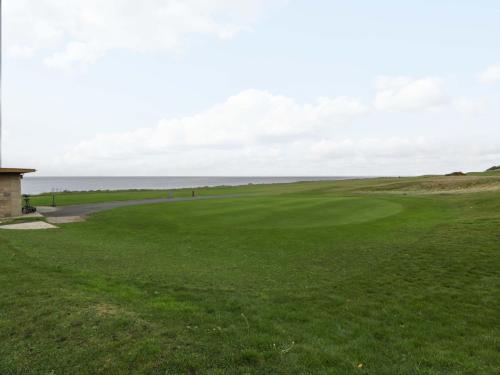 a golf course with the ocean in the background at Ailsa View in Girvan
