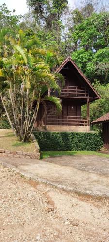 a house with a palm tree in front of it at Pousada Ypê das Montanhas in Monte Alegre do Sul